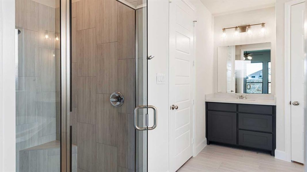 Bathroom with vanity, ceiling fan, and a shower with shower door