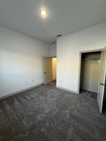 Unfurnished bedroom featuring dark colored carpet and a closet