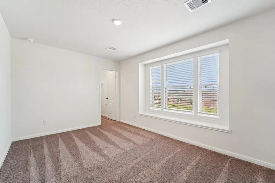 This secondary bedroom features the large picturesque window with blinds and a window shelf. It also features plush carpet flooring, neutral toned walls, recessed lighting, and a walk-in closet!