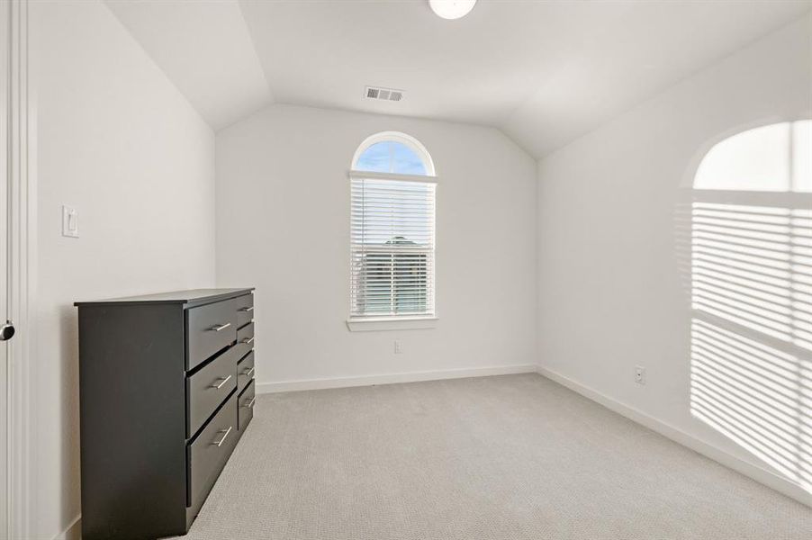Unfurnished bedroom featuring lofted ceiling and light carpet