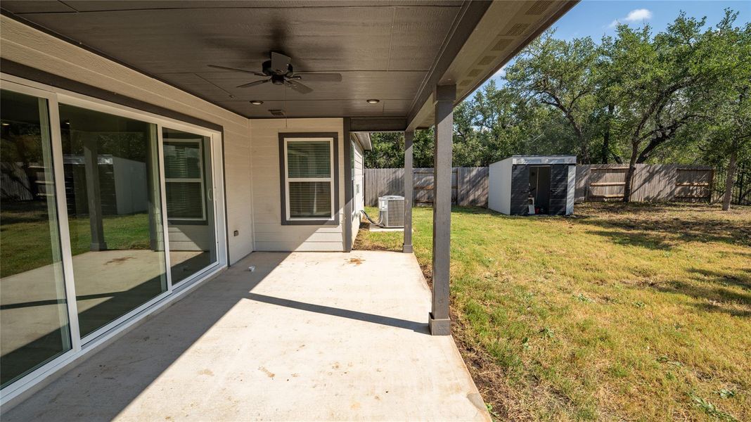 Fenced backyard featuring a shed, a patio area, and a ceiling fan Fenced backyard featuring a shed, a patio area, and a ceiling fan