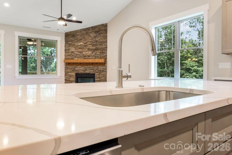 Quartz countertop on kitchen island open to great room and French doors overlooking private, wooded view.