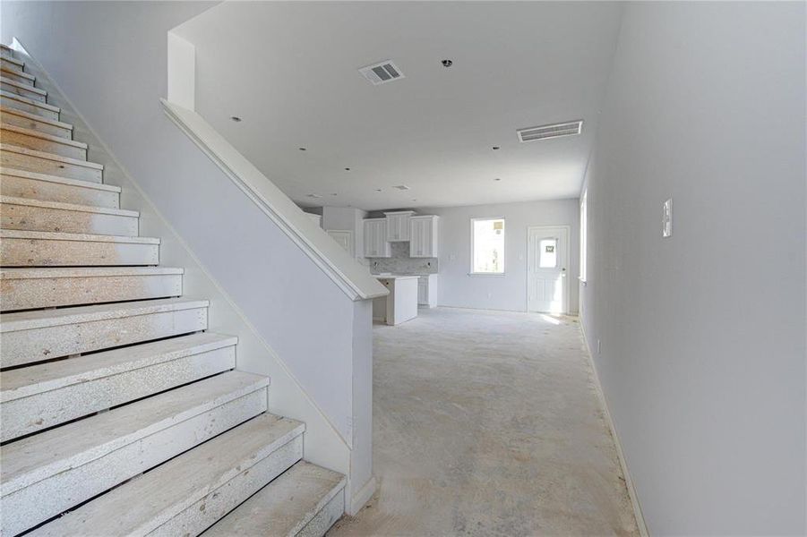 The open staircase design not only offers easy access to the upper level but also adds a modern architectural element to the main living space. This layout ensures that the home feels connected, yet distinct, between its various living areas. **This image is from another Saratoga Home - Athena floorplan.**