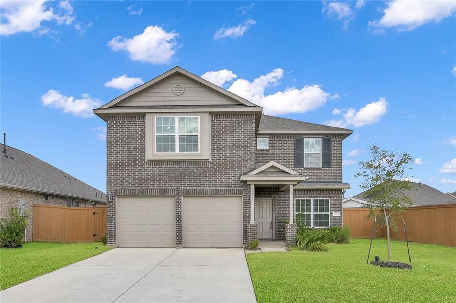 You're looking at a two-story brick home with a double garage and a neat front yard, under a blue sky with a few clouds. The house features a prominent upper window (bay window) and a welcoming entrance.