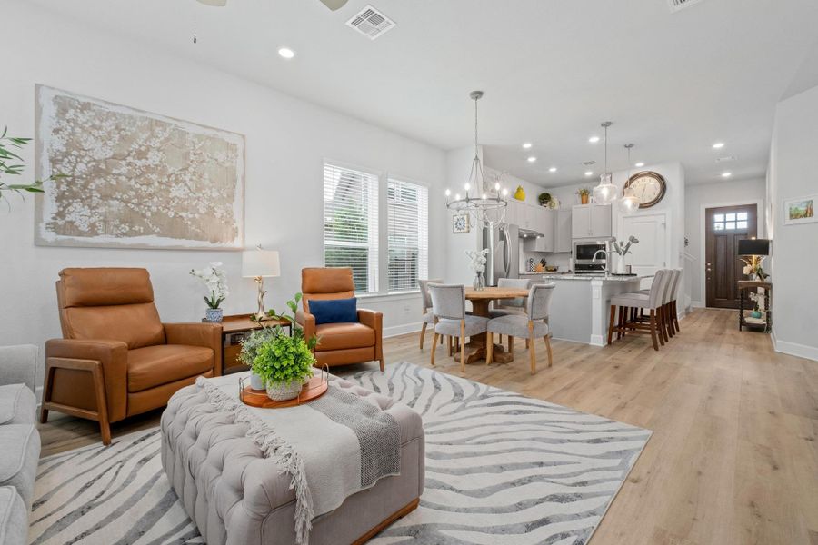 Living area with a notable chandelier, light wood finished floors, recessed lighting, baseboards, and visible vents Living area with a notable chandelier, light wood finished floors, recessed lighting, baseboards, and visible vents