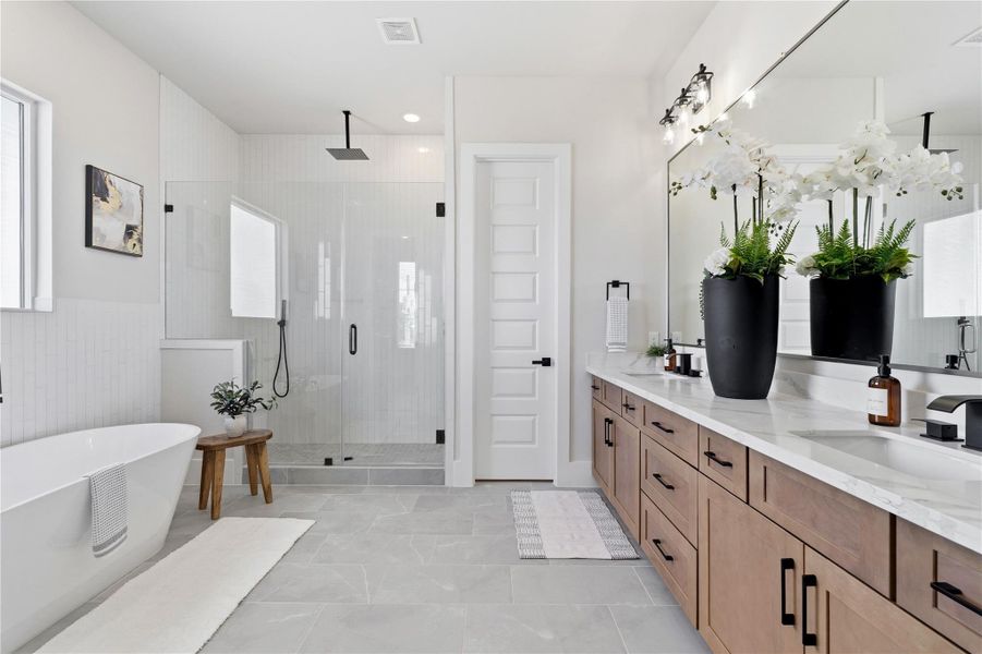 A spacious primary bathroom designed with clean lines, featuring a freestanding soaking tub, glass-enclosed shower, and expansive double vanity. A spacious primary bathroom designed with clean lines, featuring a freestanding soaking tub, glass-enclosed shower, and expansive double vanity.