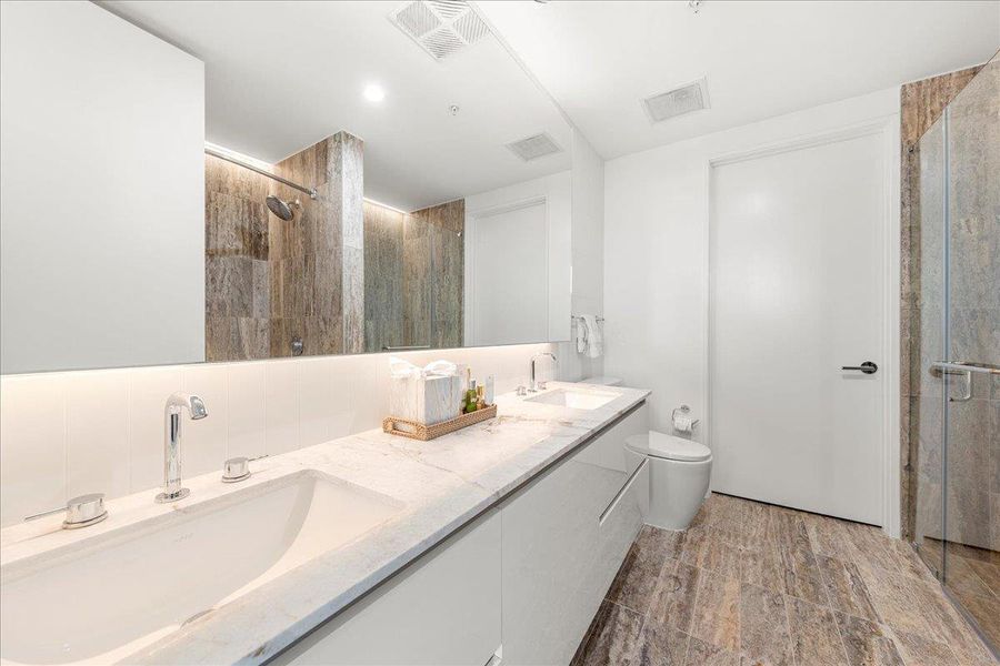 Spa-inspired primary ensuite with dual vanities, a soaking tub, walk-in shower and sleek stone finishes throughout. Spa-inspired primary ensuite with dual vanities, a soaking tub, walk-in shower and sleek stone finishes throughout.