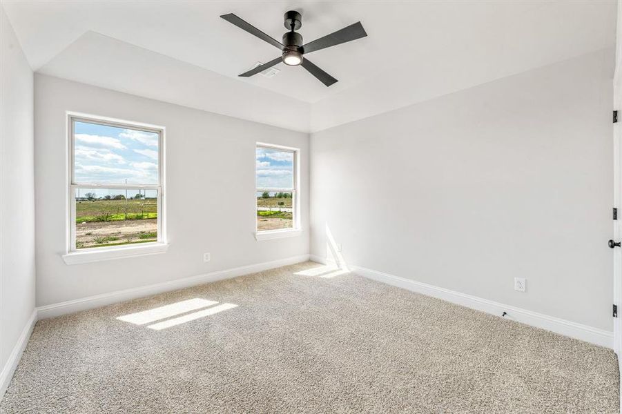 Carpeted spare room featuring baseboards and ceiling fan