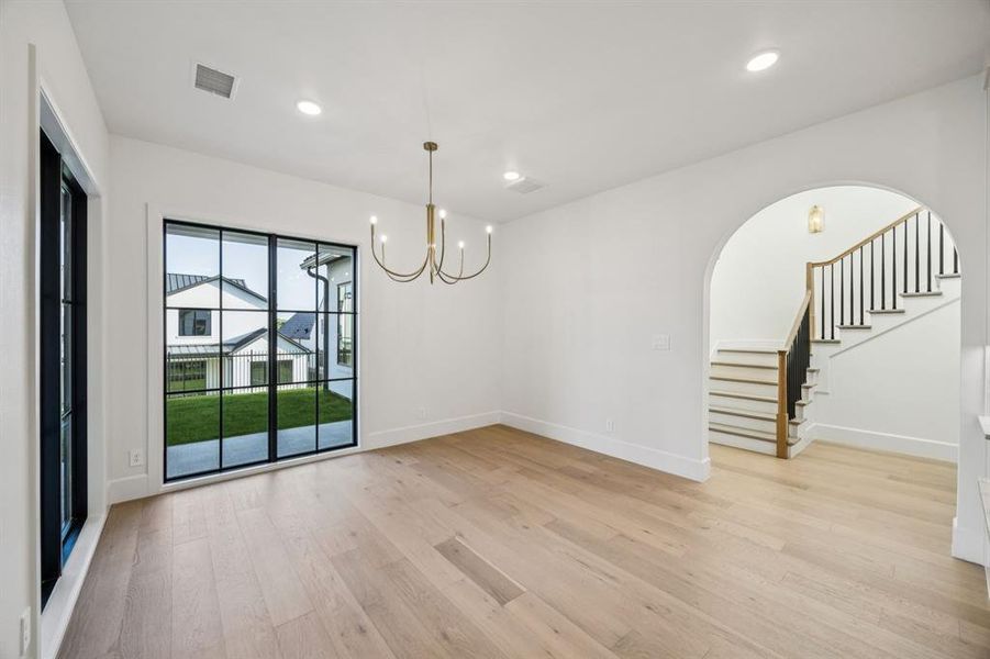 Unfurnished room featuring a chandelier, arched walkways, light wood-style flooring, stairway, and recessed lighting Unfurnished room featuring a chandelier, arched walkways, light wood-style flooring, stairway, and recessed lighting