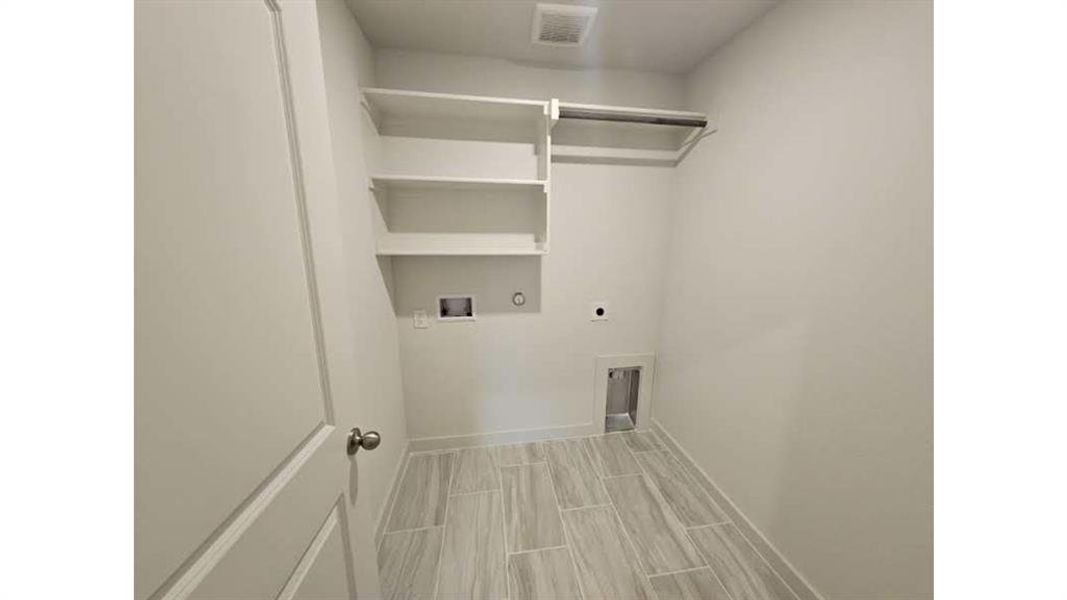 Utility area featuring light wood-finish plank flooring, built-in shelving, and a hanging rod