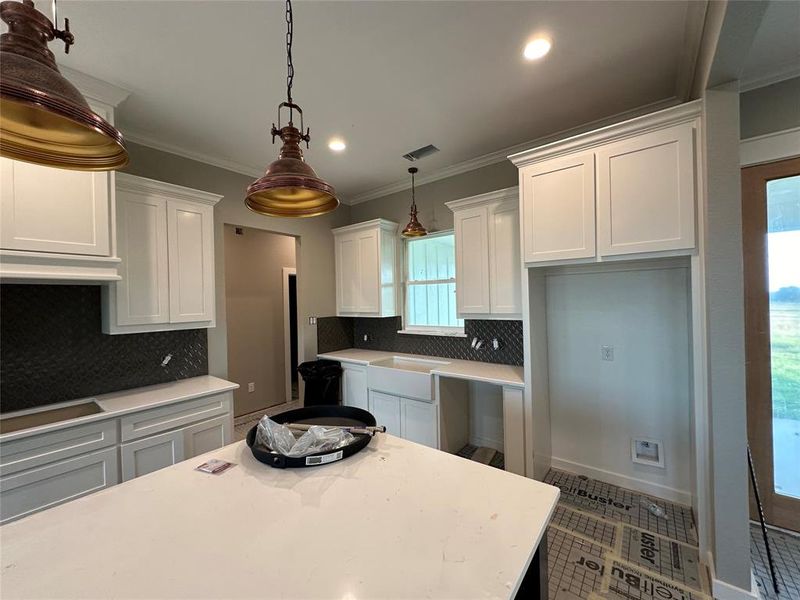 Kitchen featuring decorative light fixtures, white cabinetry, and a wealth of natural light