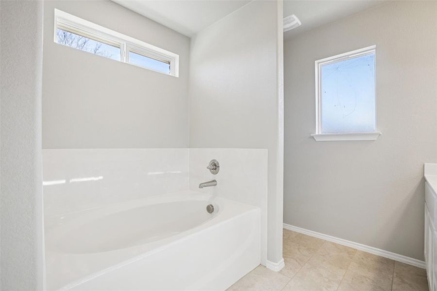 Full bathroom featuring a garden tub, vanity, and light tile patterned floors