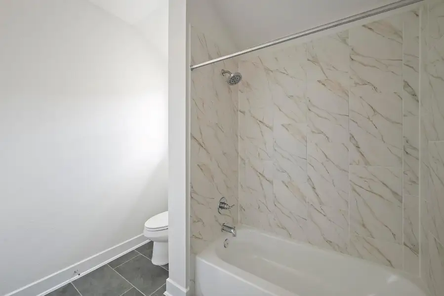 Full bath with baseboards, tile patterned flooring, toilet, and tub / shower combination