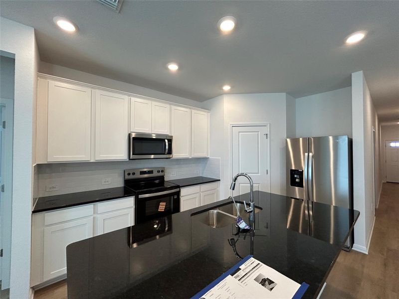 Kitchen with appliances with stainless steel finishes, decorative backsplash, white cabinets, dark wood-style floors, and recessed lighting Kitchen with appliances with stainless steel finishes, decorative backsplash, white cabinets, dark wood-style floors, and recessed lighting