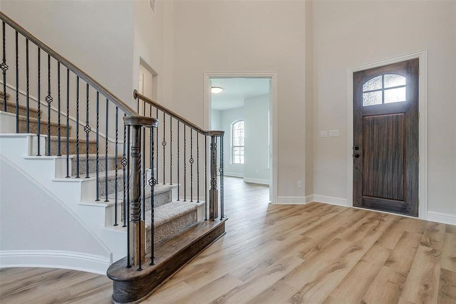 Foyer featuring plenty of natural light, light hardwood / wood-style floors, and a towering ceiling