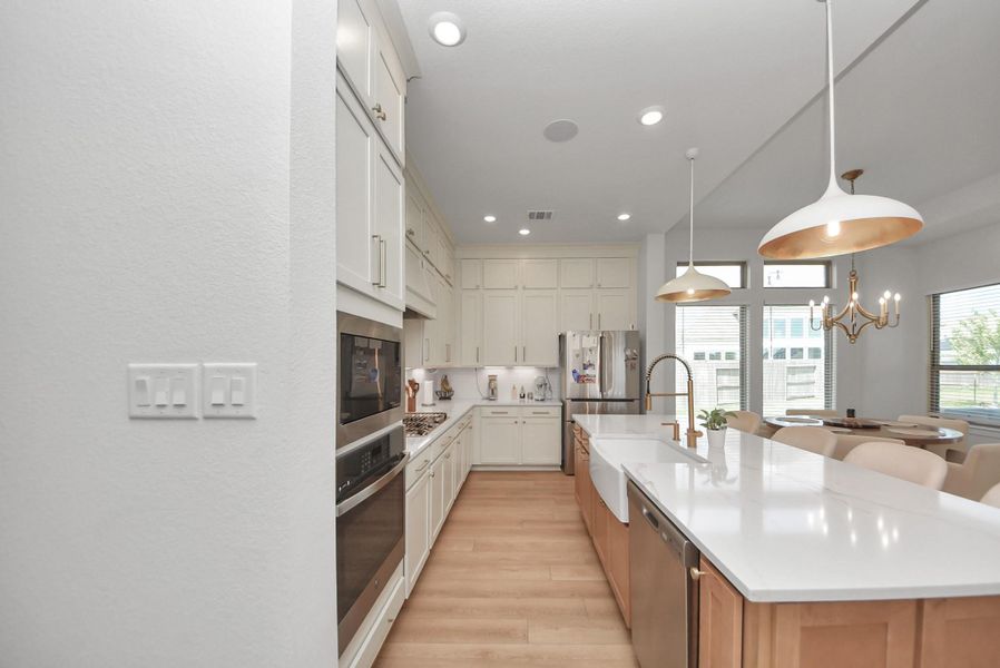 Sleek modern kitchen with high-end appliances, elegant cabinetry, and a spacious island with pendant lighting, seamlessly flowing into a bright dining area.