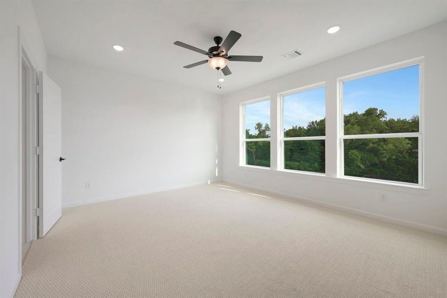 Room featuring three large windows showcasing a verdant tree line