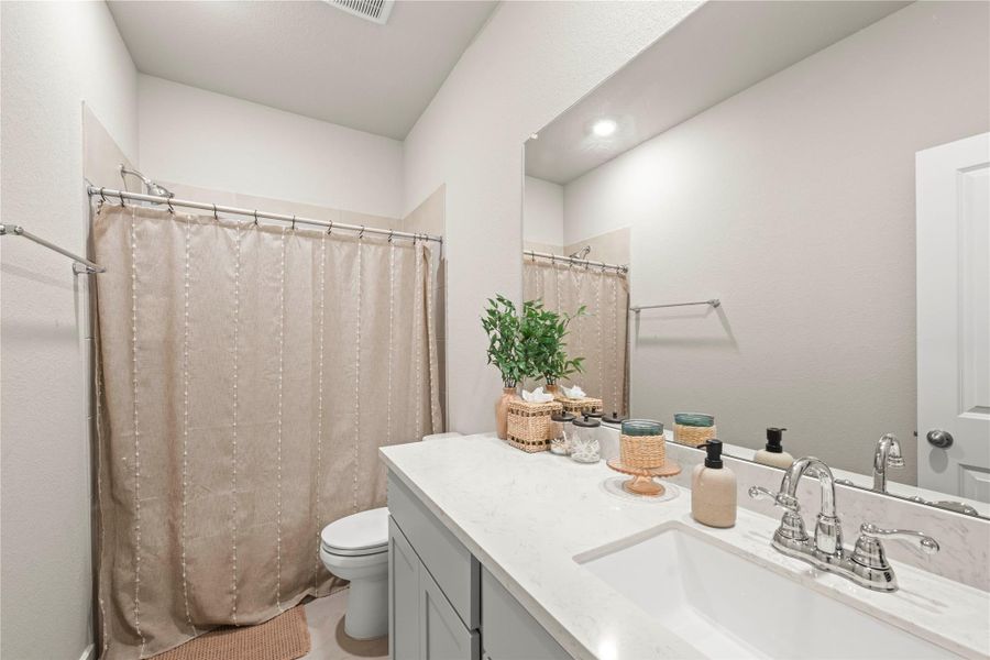 White quartz countertops and modern fixtures appoint this well-lit bath. White quartz countertops and modern fixtures appoint this well-lit bath.