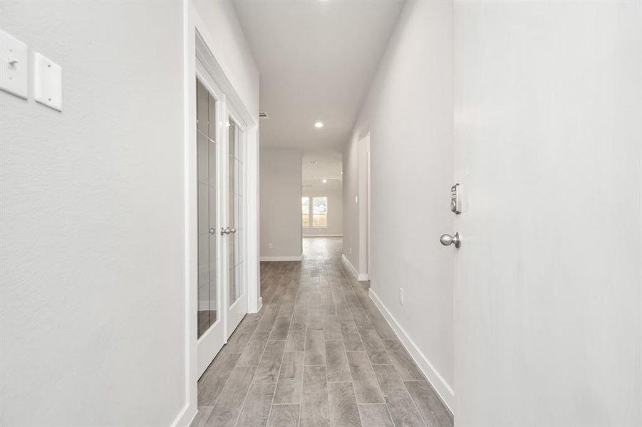 The grand entrance beckons with high ceilings, adorned with elegant wood-look tile flooring and oversized baseboards. Sample photo of completed home with similar floor plan. As-built interior colors and selections may vary.