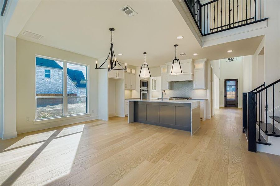 Kitchen featuring a chandelier, white cabinetry, a kitchen island with sink, light wood-type flooring, and recessed lighting Kitchen featuring a chandelier, white cabinetry, a kitchen island with sink, light wood-type flooring, and recessed lighting