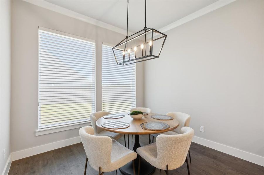 Dining area featuring a chandelier, crown molding, a wealth of natural light, and dark wood-type flooring