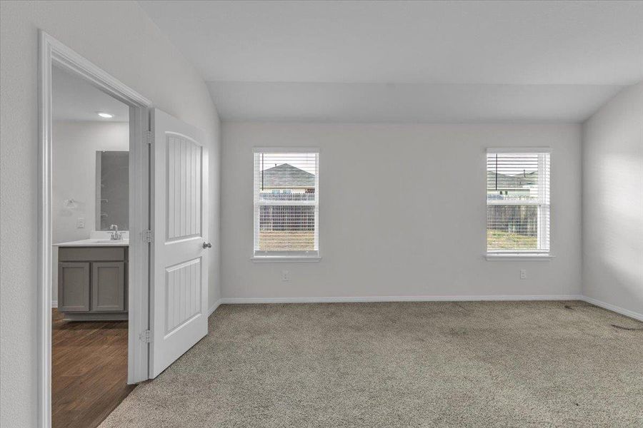 Unfurnished bedroom with lofted ceiling and light colored carpet