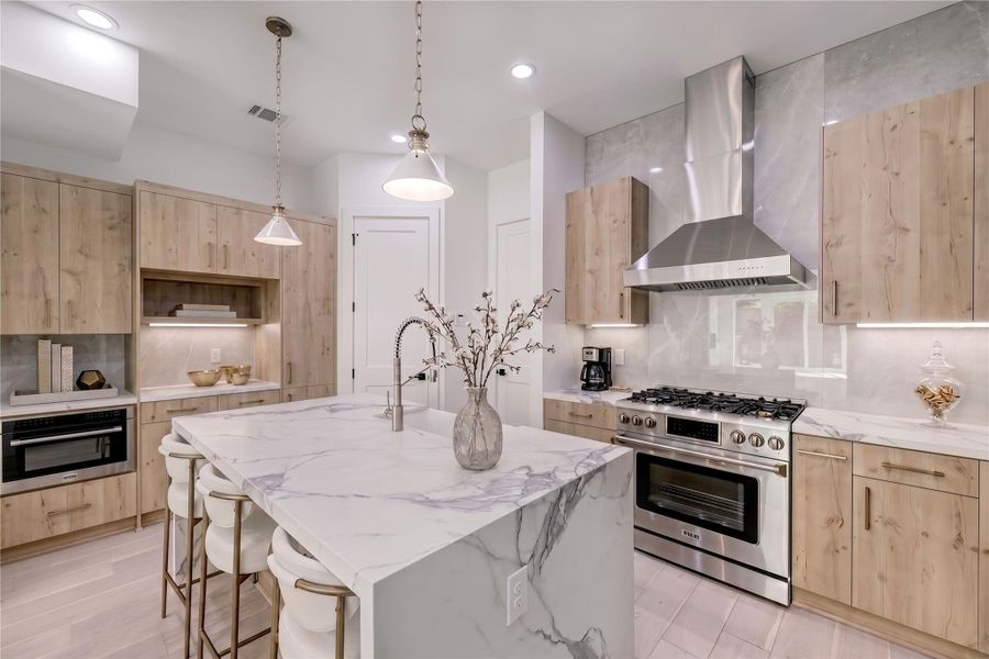 Kitchen features stainless steel appliances, custom pendants and porcelain tile backsplash.