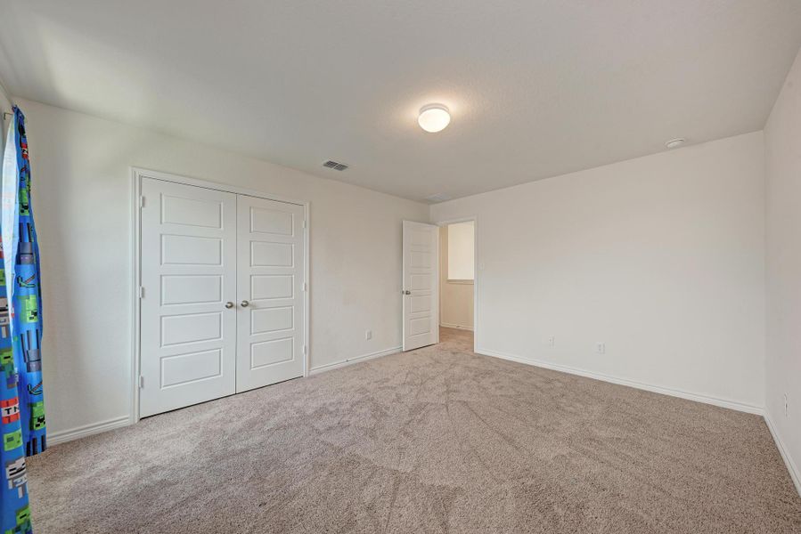 A well-lit bedroom with fresh, neutral walls and soft carpeting invites tranquil rest.