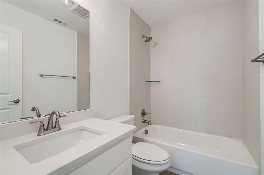 Full bathroom featuring toilet, tiled shower / bath, and vanity