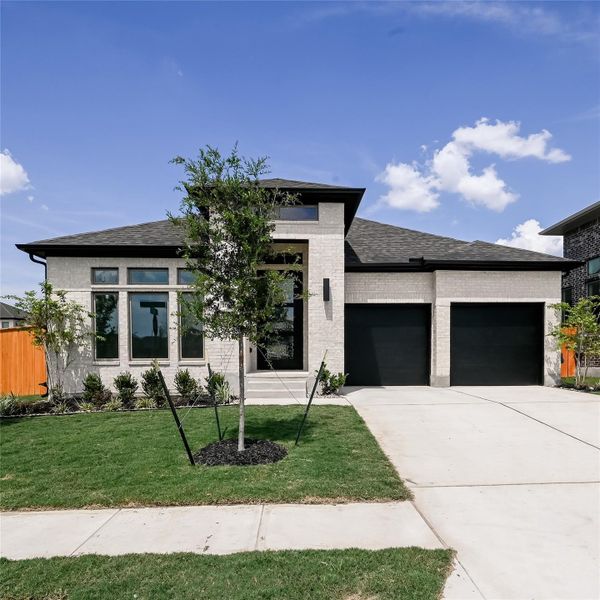 Prairie-style house with an attached garage, driveway, brick siding, a front lawn, and roof with shingles Prairie-style house with an attached garage, driveway, brick siding, a front lawn, and roof with shingles