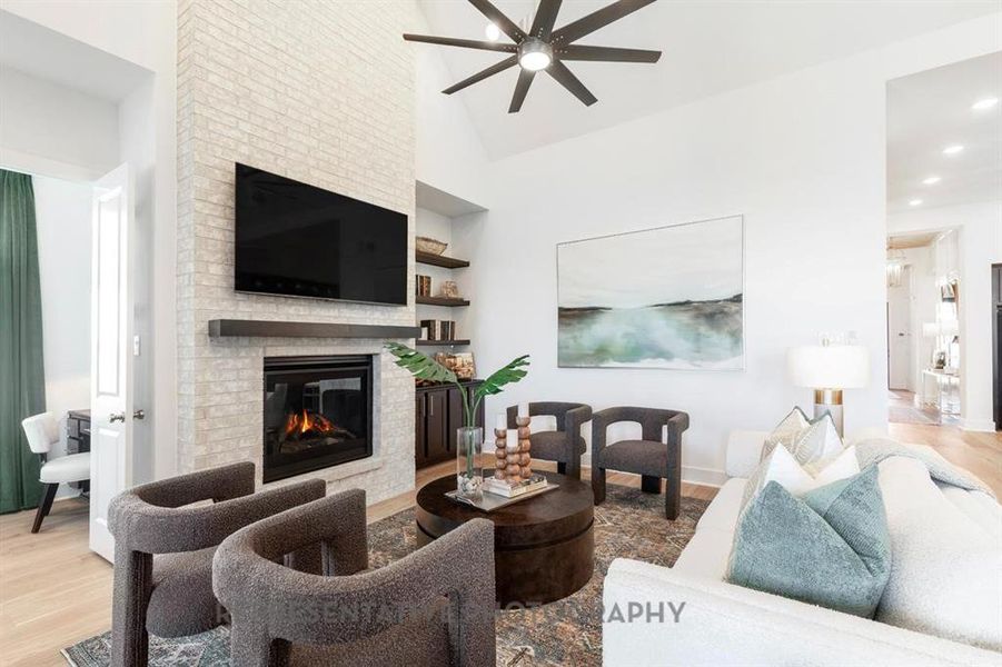Living area featuring light wood finished floors, a fireplace, high vaulted ceiling, ceiling fan, and recessed lighting