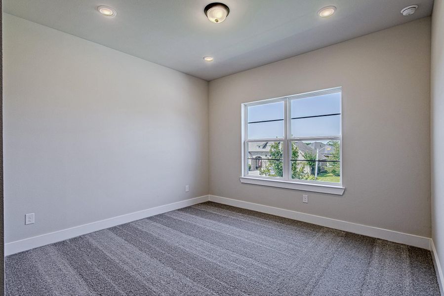 Additional secondary bedroom with carpeted flooring and a large window