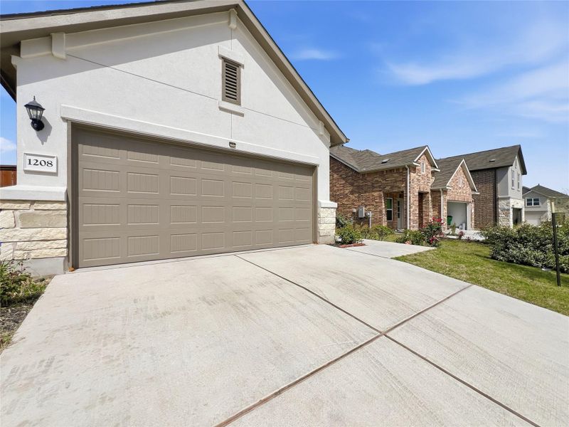 Ranch-style house featuring stone siding, a garage, stucco siding, and driveway