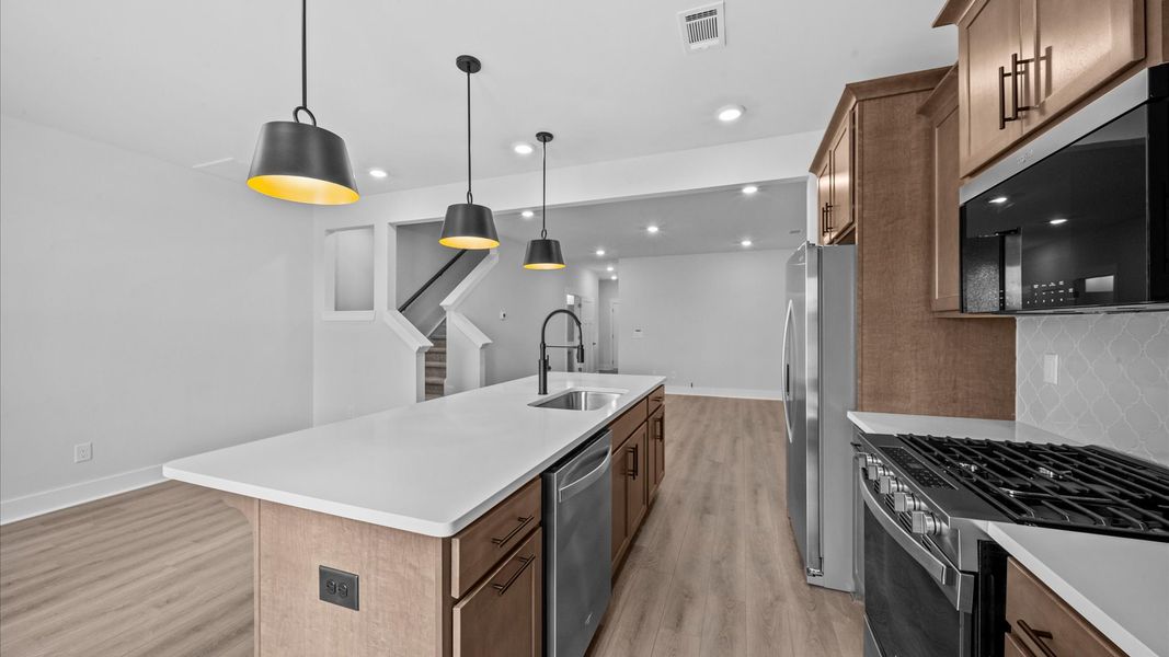 Modern open concept kitchen with wooden cabinetry in two story townhome at Ransdell Pointe by DRB Homes in Spartanburg, SC