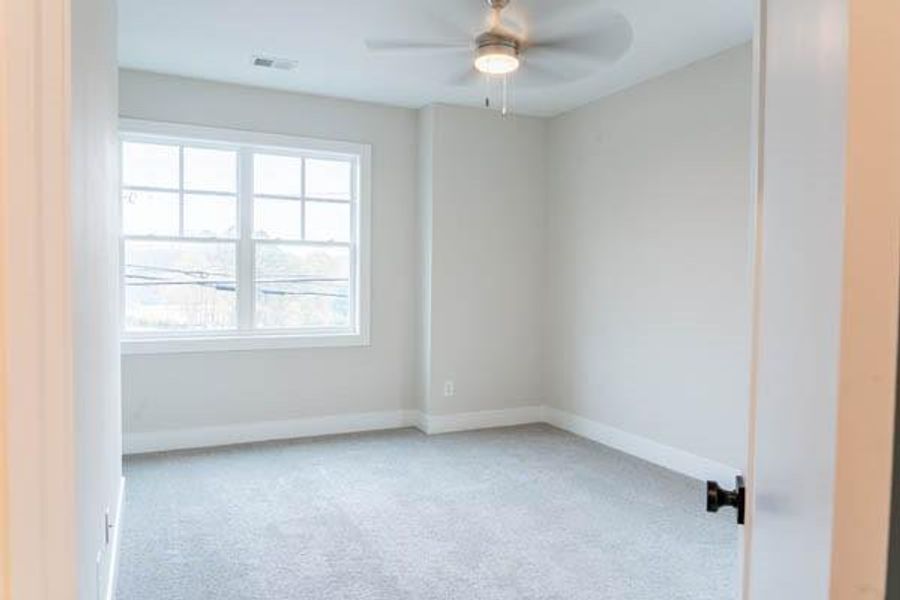 Carpeted empty room featuring a wealth of natural light and ceiling fan Carpeted empty room featuring a wealth of natural light and ceiling fan