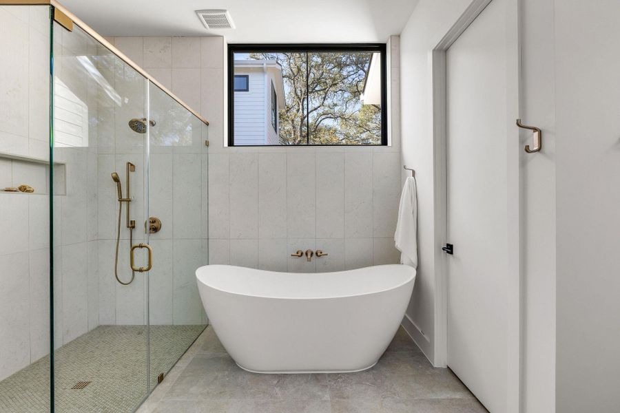 Full bath with a shower stall, a soaking tub, and tile walls