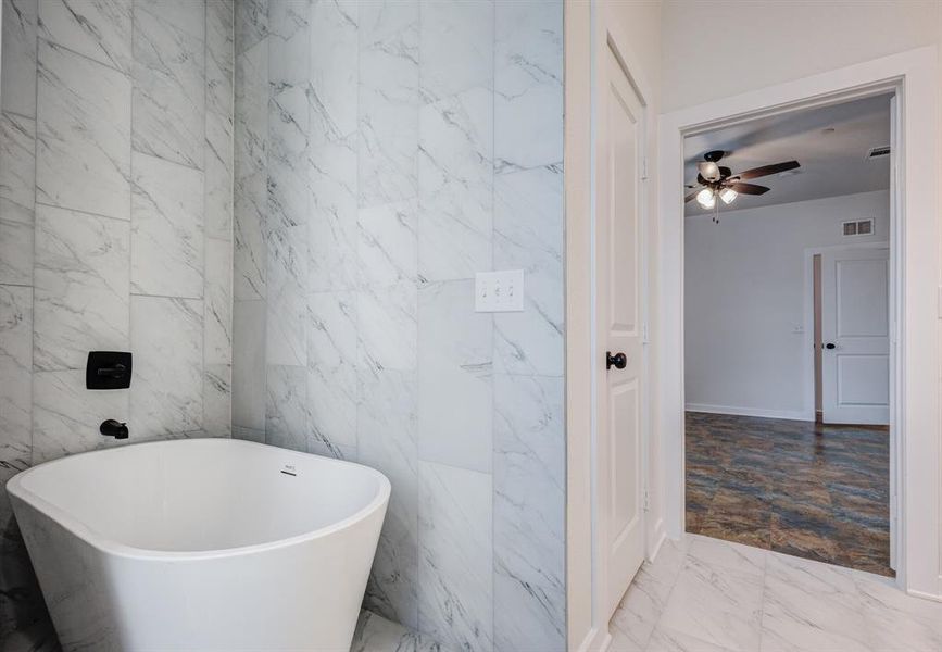 Bathroom featuring a bathing tub, tile patterned flooring, ceiling fan, and tile walls