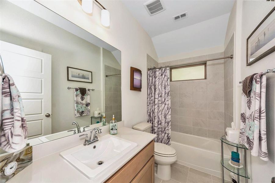 Full bathroom with vanity, shower / bath combination with curtain, tile patterned flooring, and toilet