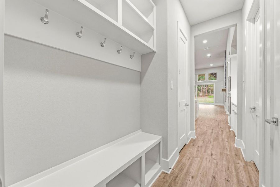 Mud room with custom shelves and coat closet walking in from garage.