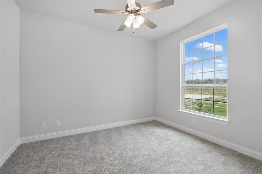 Empty room featuring carpet floors, baseboards, and a ceiling fan