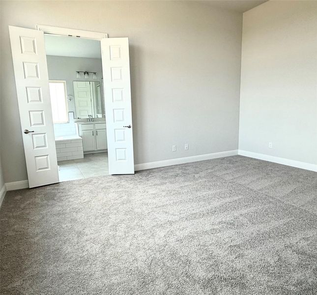 Unfurnished bedroom featuring light colored carpet and ensuite bath Unfurnished bedroom featuring light colored carpet and ensuite bath