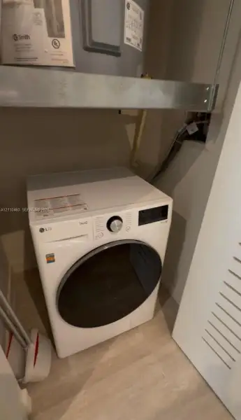Utility closet featuring a dedicated water heater and light-toned tile flooring
