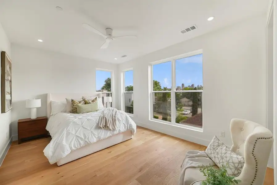 Bright bedroom featuring wide plank wood-finish flooring, recessed lighting, and a ceiling fan Bright bedroom featuring wide plank wood-finish flooring, recessed lighting, and a ceiling fan