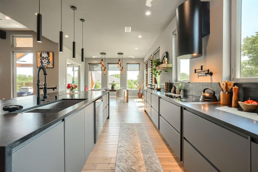 Kitchen with dark countertops, light wood finished floors, decorative light fixtures, modern cabinets, and recessed lighting Kitchen with dark countertops, light wood finished floors, decorative light fixtures, modern cabinets, and recessed lighting