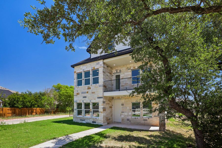 Textured stone siding and a private balcony define this modern multi-level exterior.