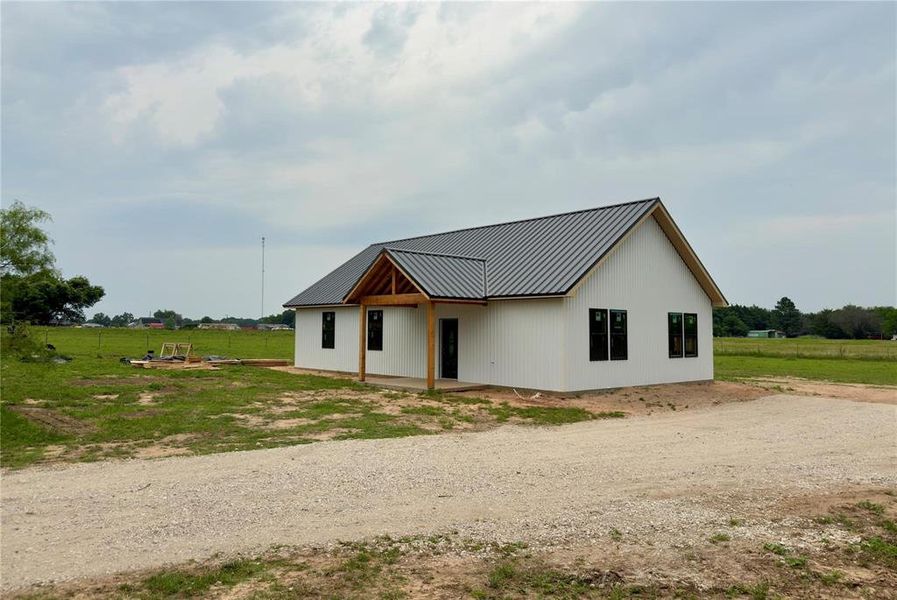 View of front of property featuring a metal roof, a rural view, and a front yard