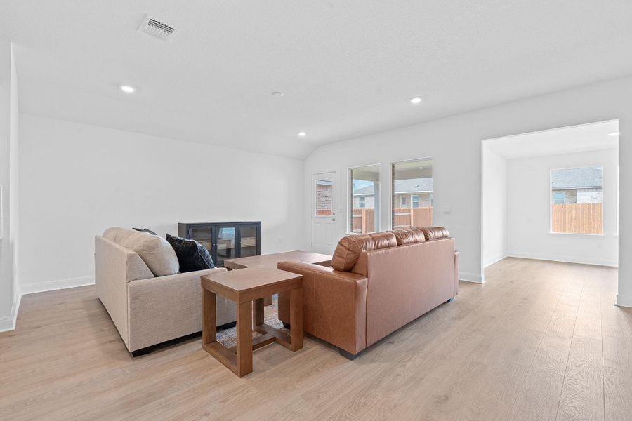Living room with light wood finished floors, recessed lighting, and vaulted ceiling Living room with light wood finished floors, recessed lighting, and vaulted ceiling