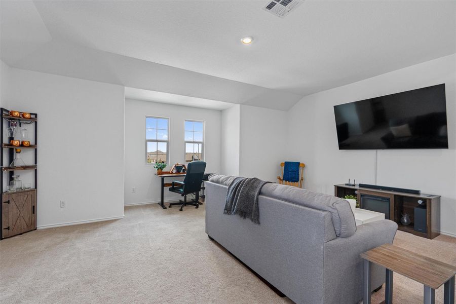 Living area featuring a desk, light carpet, vaulted ceiling, and recessed lighting