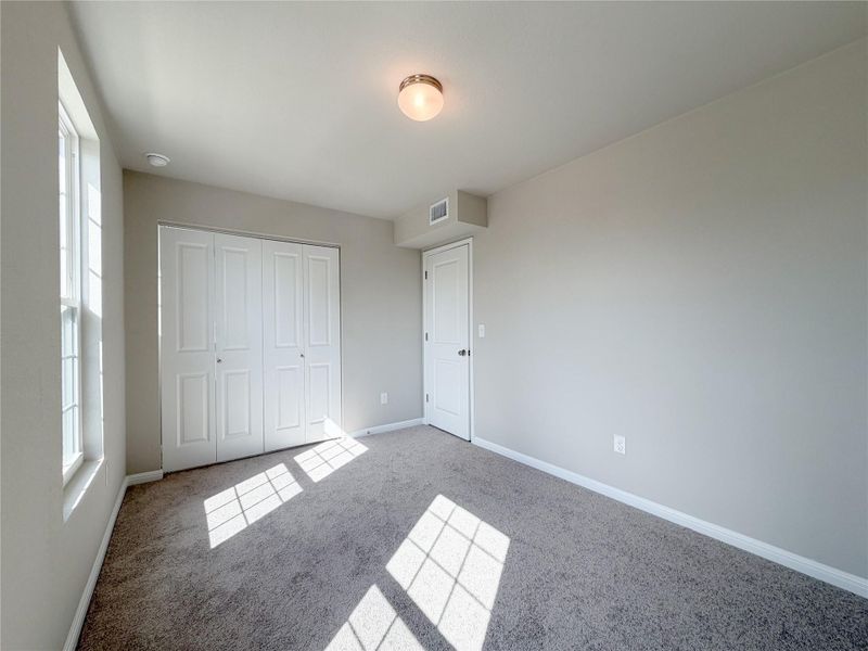 Neutral-toned room featuring a window with white trim, gray carpet flooring, and a flush mount ceiling light fixture