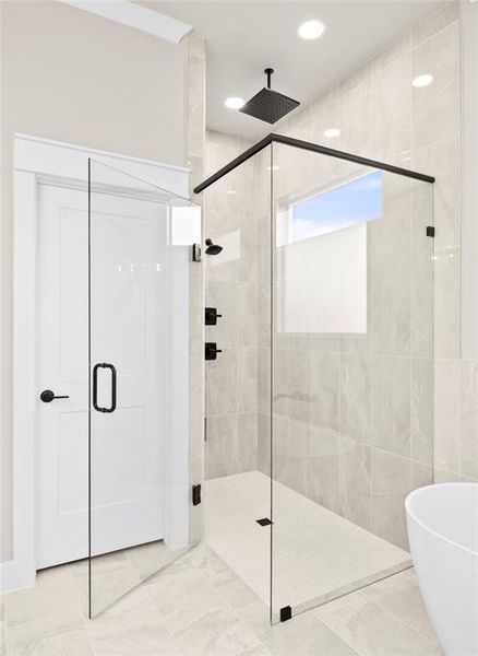 Full bath with a shower stall, a freestanding bath, and recessed lighting